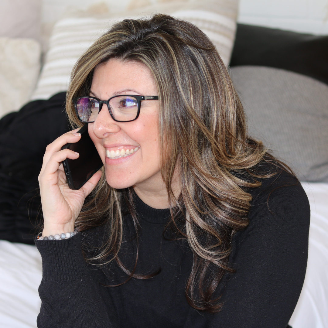 Stephanie is sitting, working on her laptop, drinking coffee, offering advice and showing her business cards