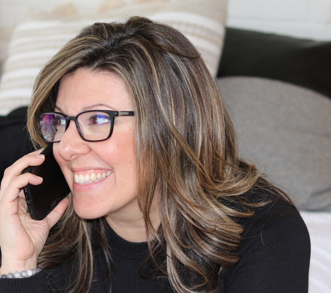 Stephanie is sitting, working on her laptop, drinking coffee, offering advice and showing her business cards