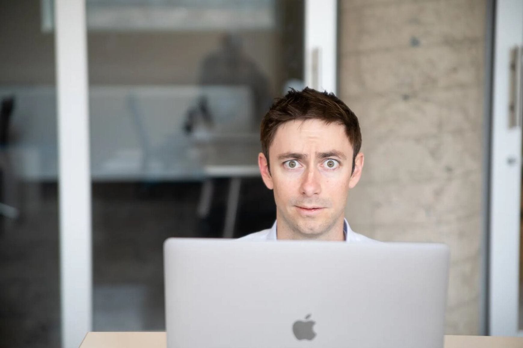 Man looking up from computer screen and looking confused