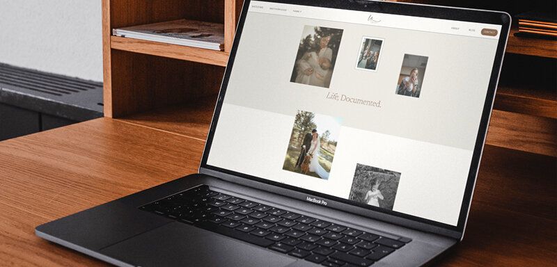 Laptop with modern showit website displayed sitting on wooden desk with pottery.