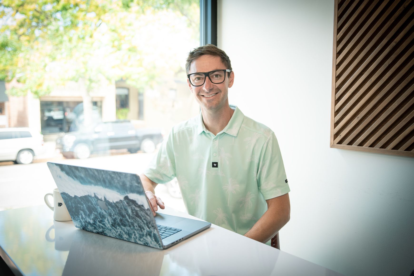 Connor Walberg smiling while working at laptop in modern workspace