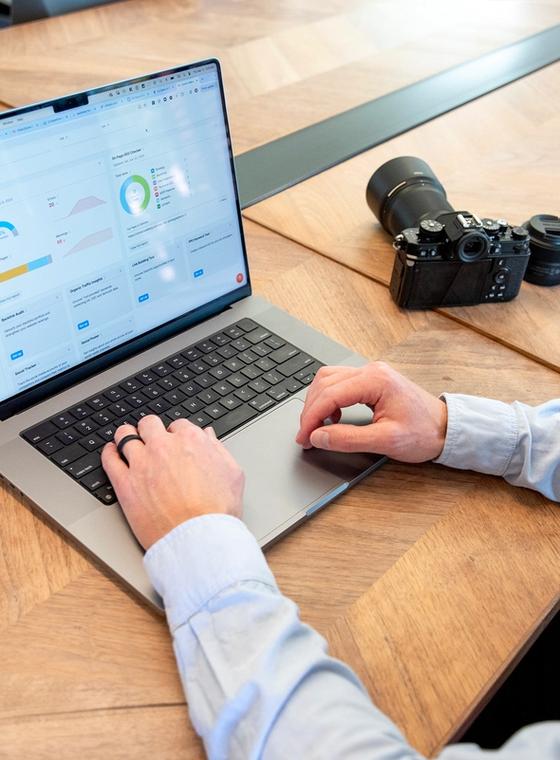 man checking SEO report for photographers website with camera on desk.