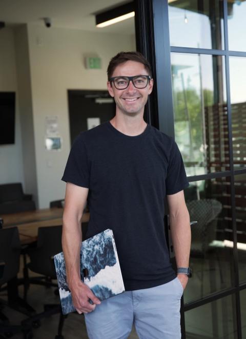 Connor Walberg standing with laptop in modern office space