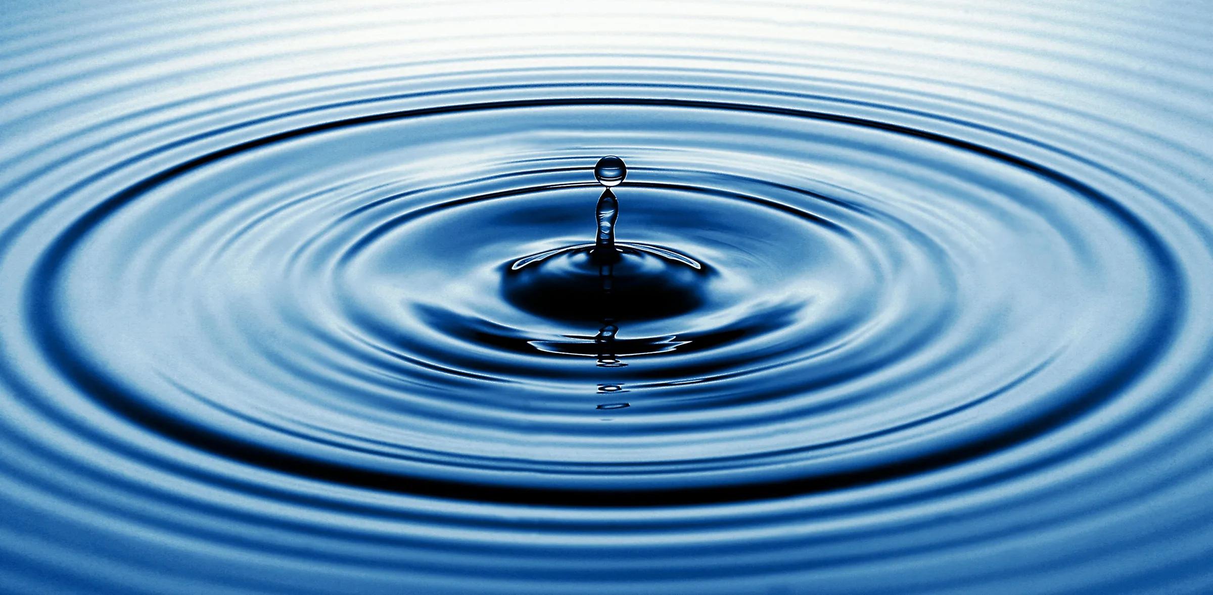 Water droplet and concentric ripples Close-up of a water droplet creating concentric ripples on a blue surface
