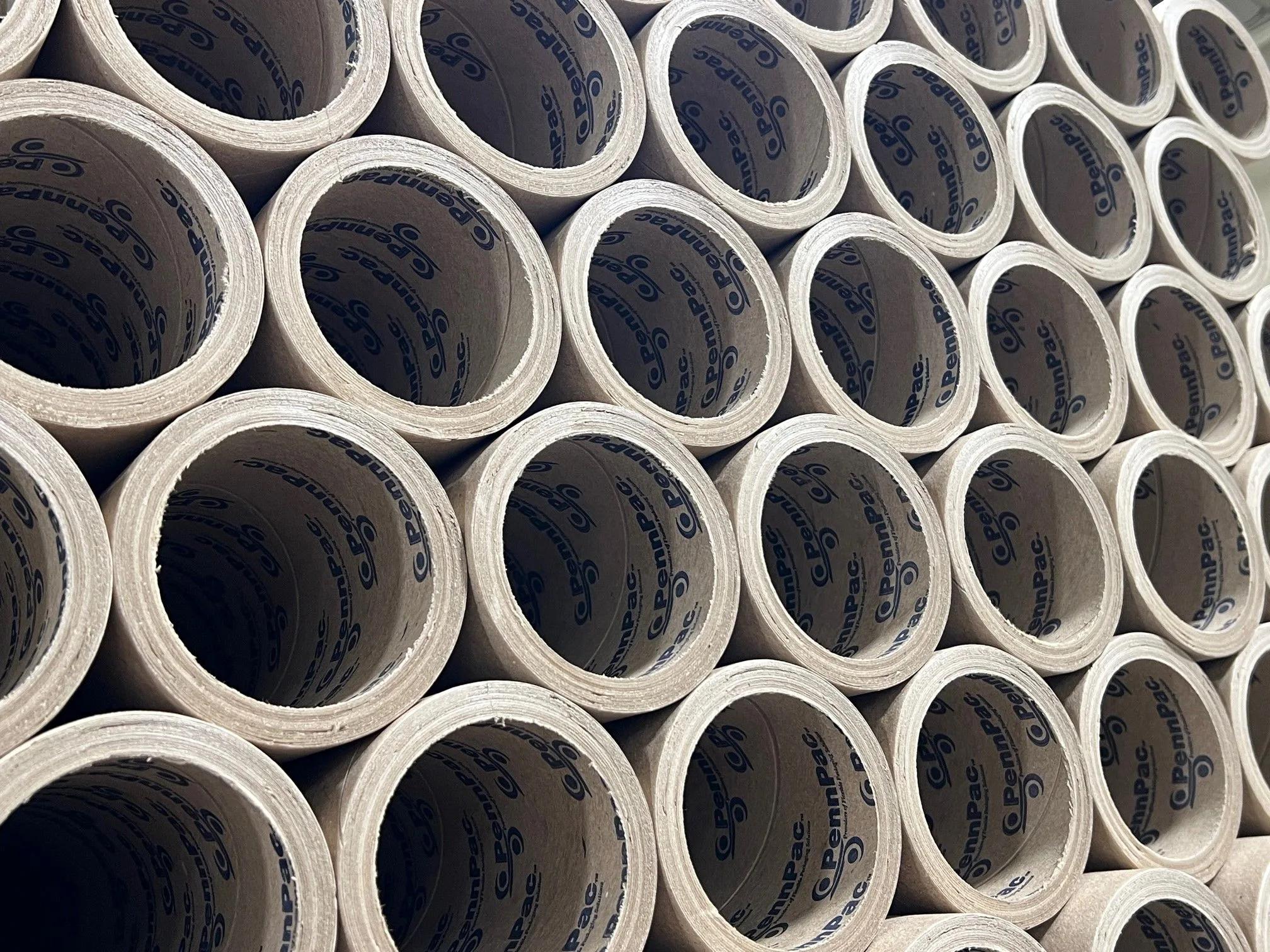 Stacked PennPac film cores Close-up of stacked cardboard film cores with 'PennPac' printed on the inner liners, arranged in repeating rows.