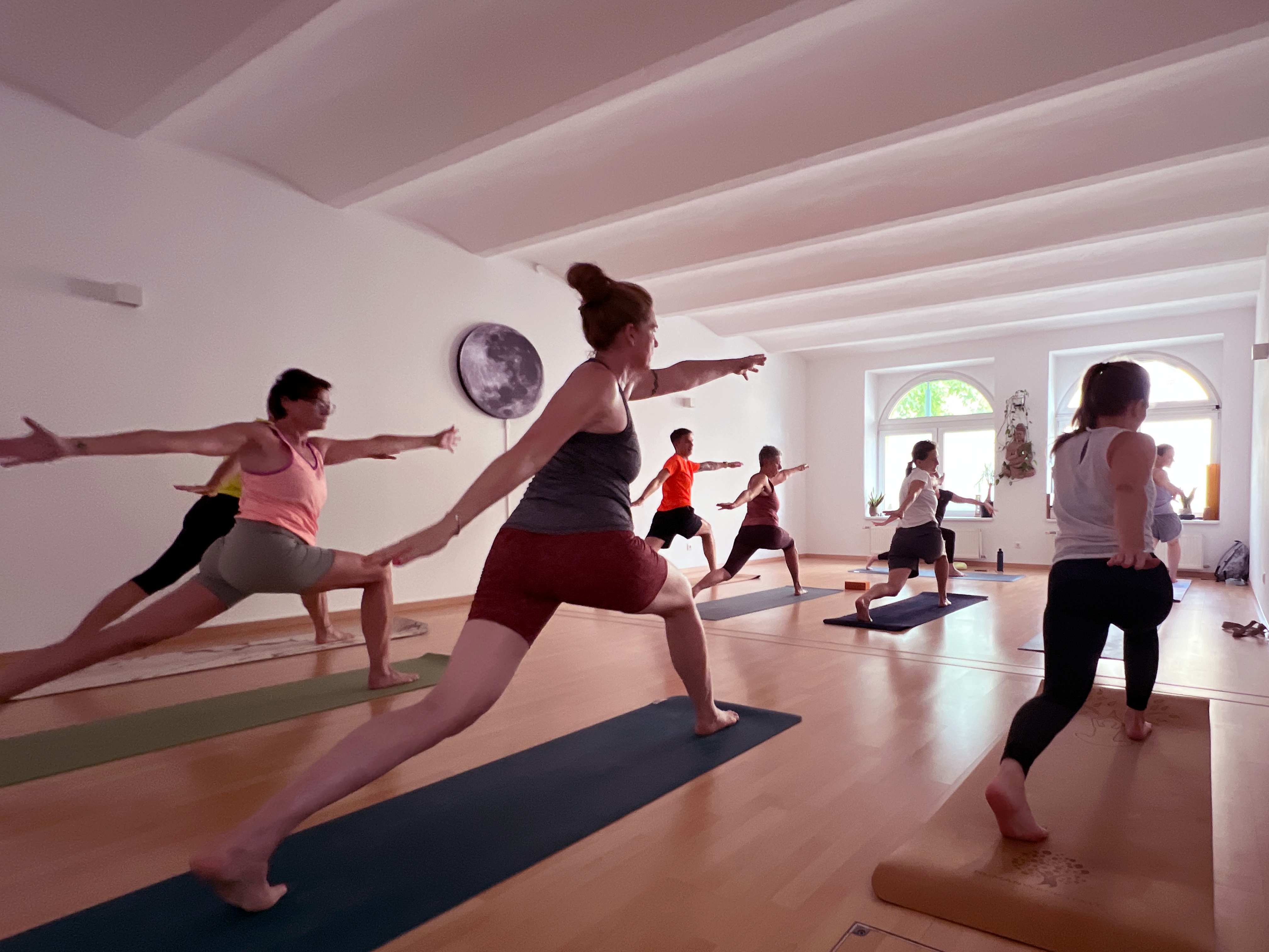 Menschen praktizieren Yoga in einem hellen beYOUnited Studio.