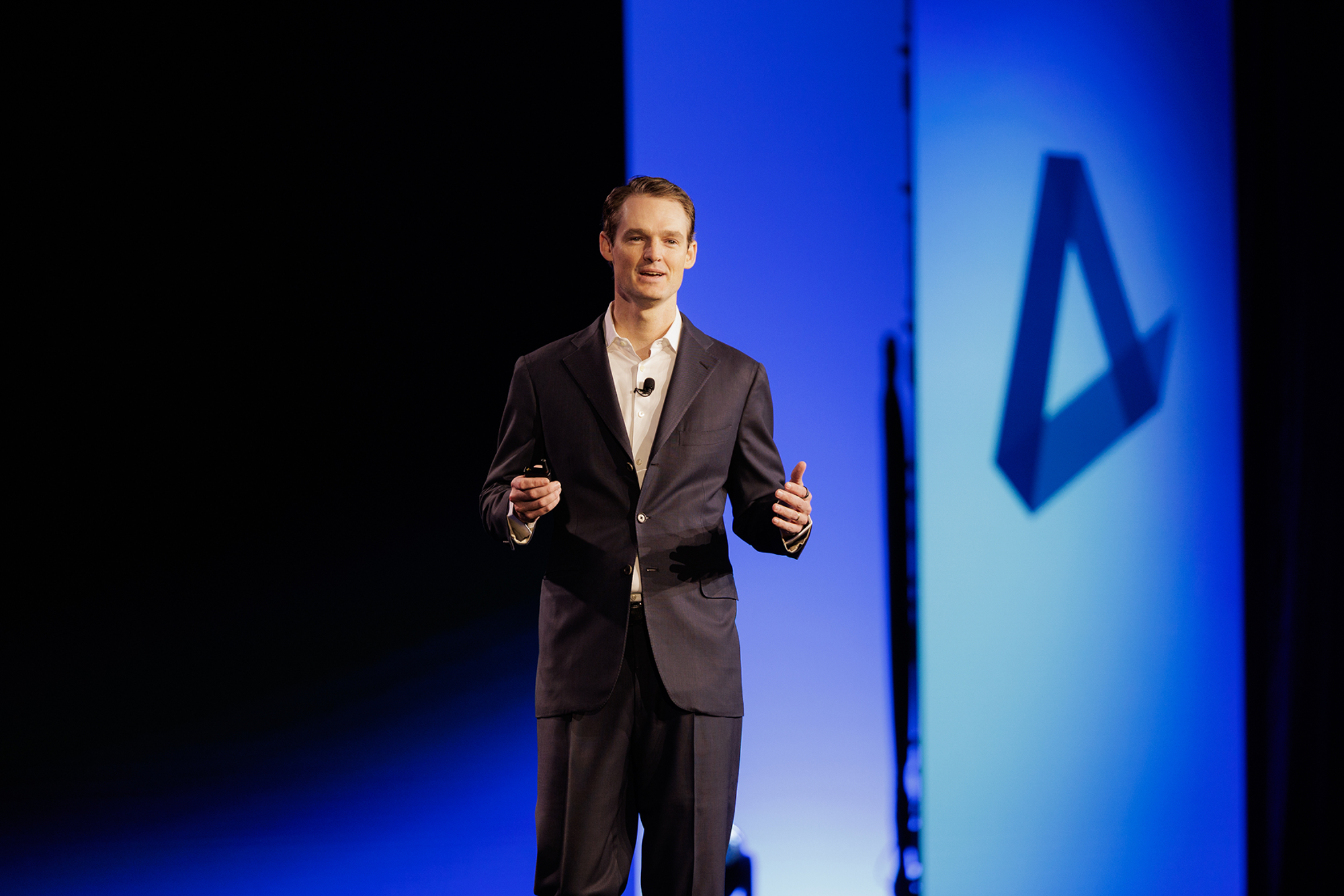 Main-stage keynote: brand mark, lighting, and LED scenography built as one cinematic system.