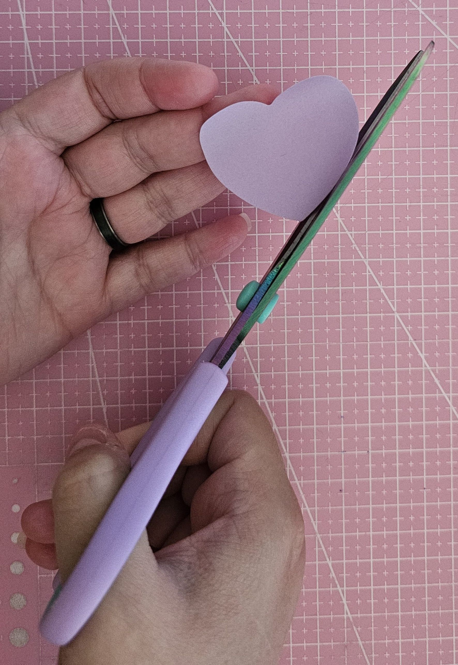 Imagen de una mano cortanzo una forma de corazon con la tijera