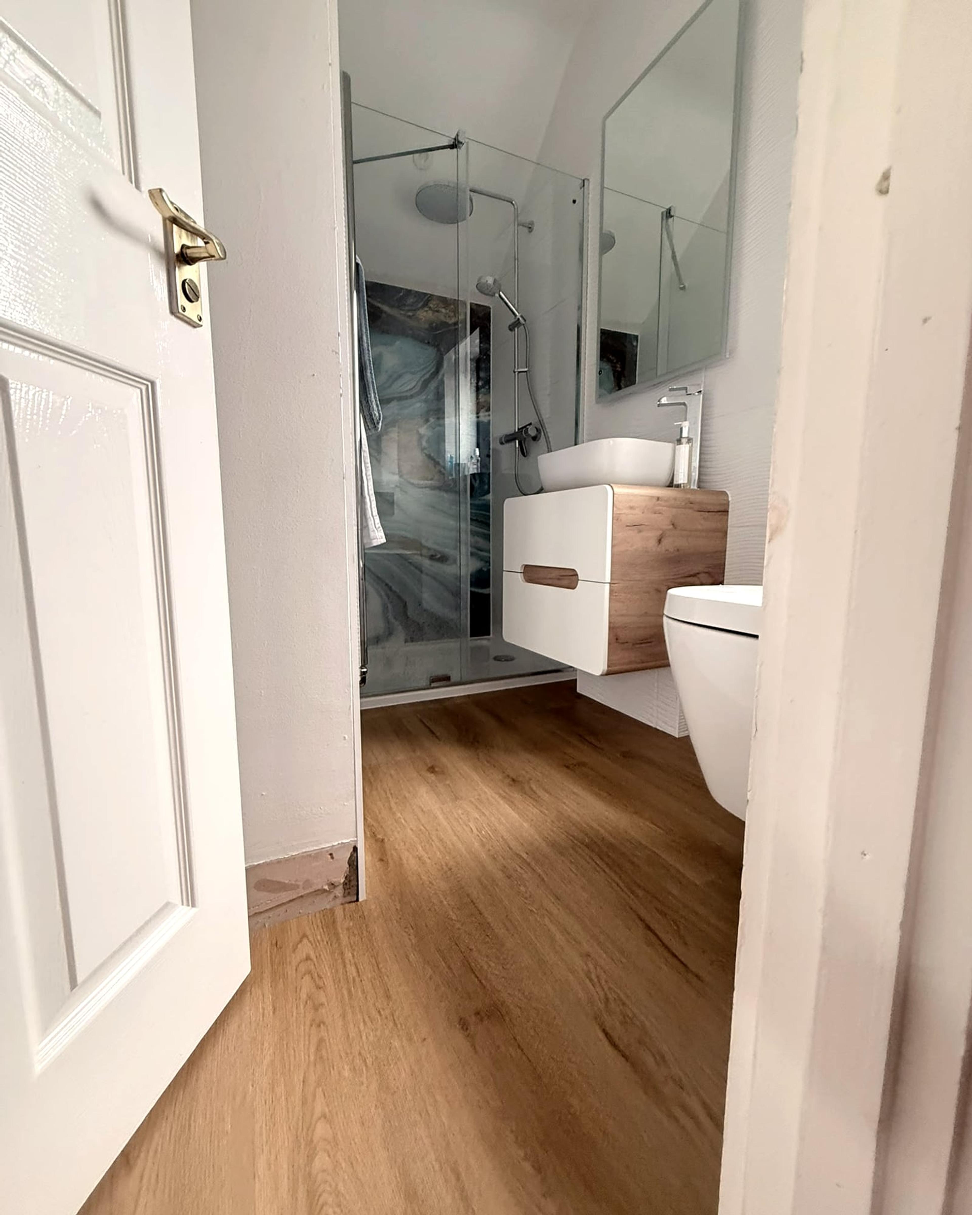 The en suite through its open door: the shower enclosure, the oak vanity unit and a mirror