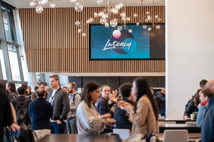 Attendees mingling under the Latency screen at Latency 2023
