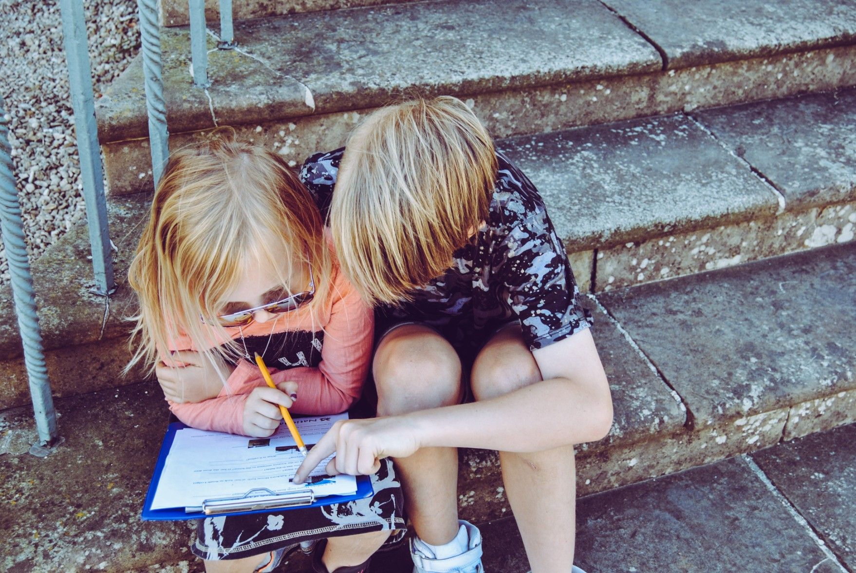 two kids helping each other with a worksheet