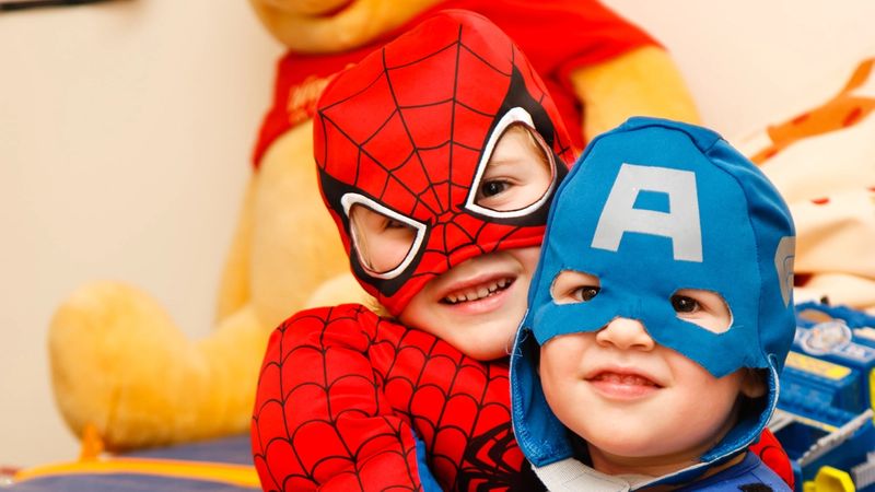 two young kids wearing super hero costumes hugging