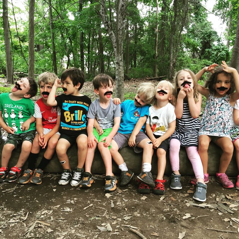 kids on a log at summer camp wearing fake mustaches