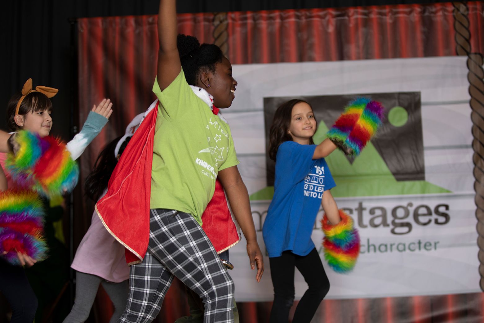 kids on stage in wacky costumes running and laughing