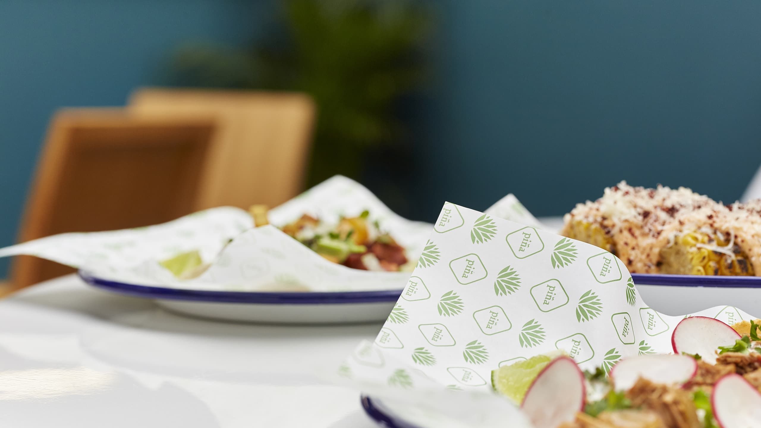A variety of piña's food served on branded greaseproof paper.