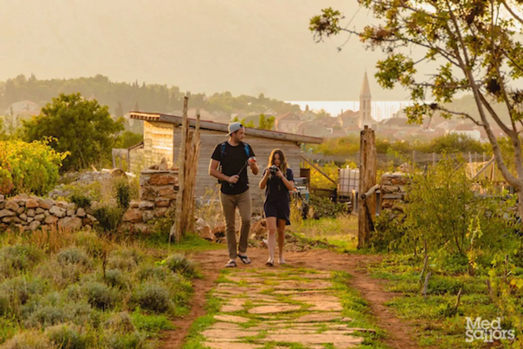 Medsailors Wine Tour Croatia. A couple walks through a sun-drenched vineyard in Hvar Island Croatia. Photo by Ryan Brown of Lost Boy Memoirs.