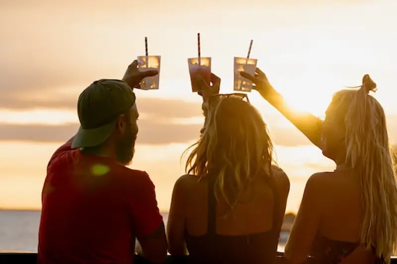 Group of people doing a cheers with cocktails at a sunset rooftop bar in Parga Greece