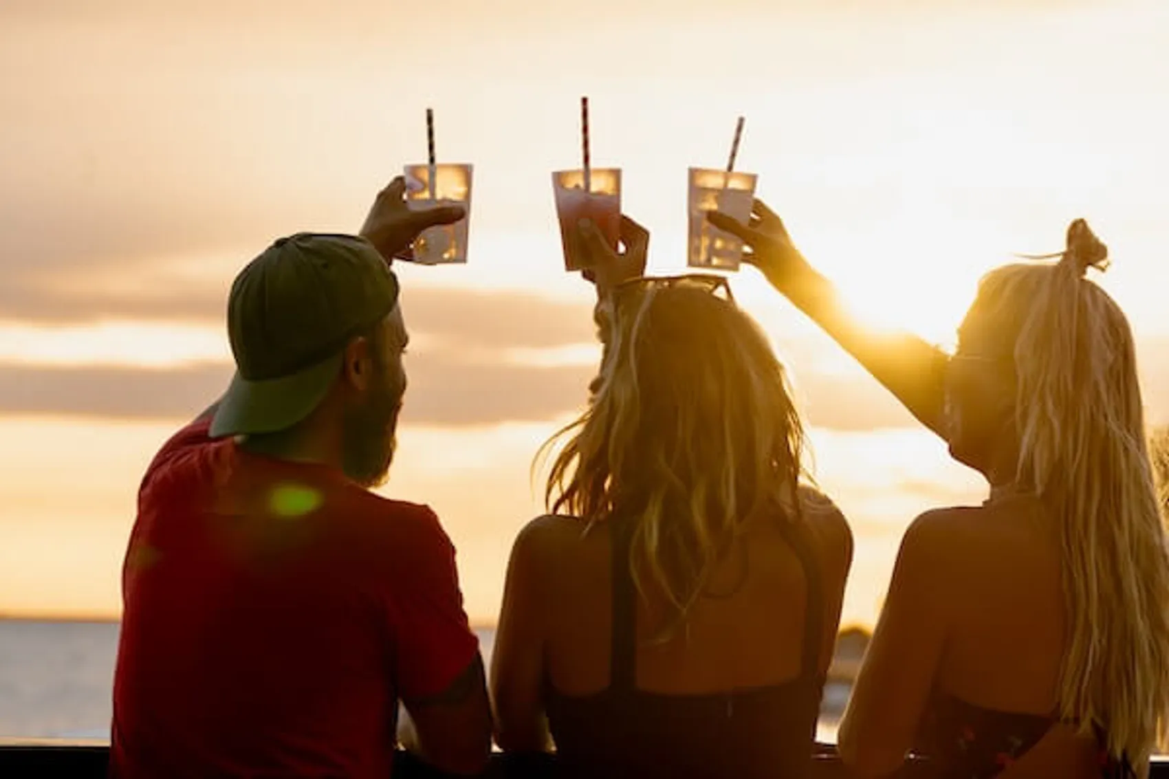 Group of people doing a cheers with cocktails at a sunset rooftop bar in Parga Greece