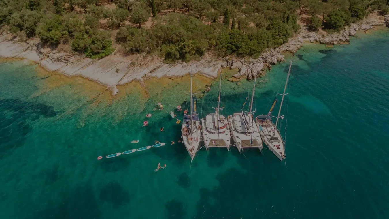 Four women on a paddleboard in clear blue water in Greece