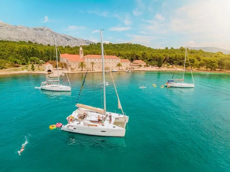 Medsailors yachts anchored in a beautiful bay with 20s and 30s travellers swimming while on their yacht week sailing holiday in Croatia.