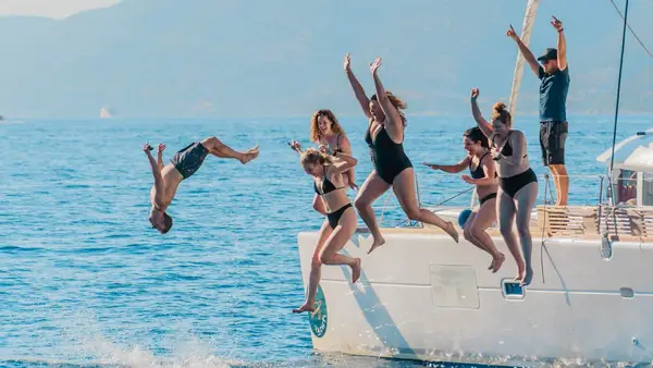 Group of friends jump off a yacht into the water in Greece