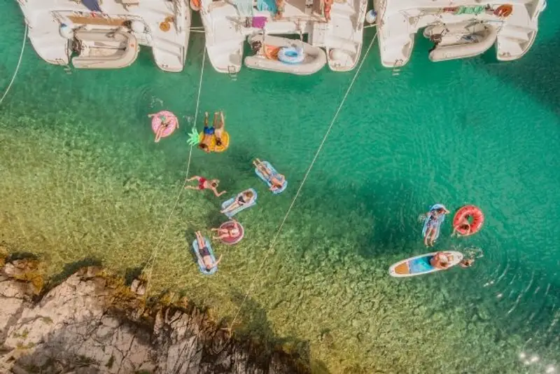 Guests floating behind boats in clear water