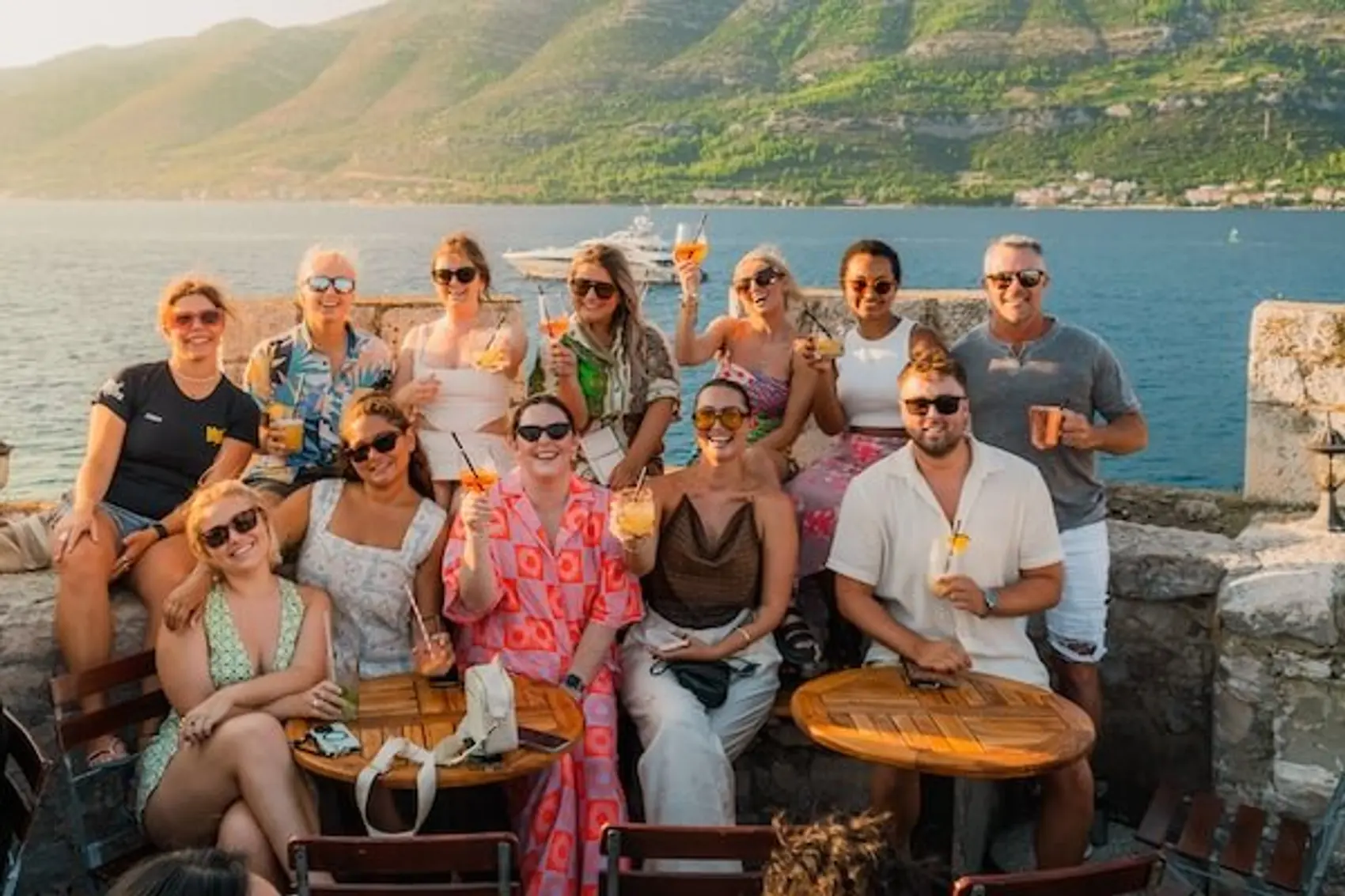 Group of people doing a cheers with cocktails at sunset atop a fortress cocktail bat in Korcula Croatia