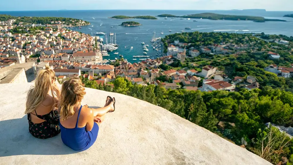 Two people sit looking at the view over Hvar Town