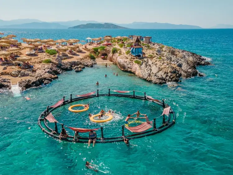 Aerial photo of the blue lagoon of Agistri at Aponisos bay, with floating hammocks and turquoise waters, easily visited on a sailing holiday from Athens.