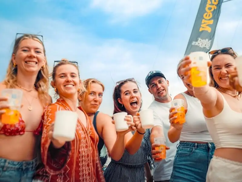 Group of friends holding drinks and smiling at a summer event in Croatia during a social group trip.