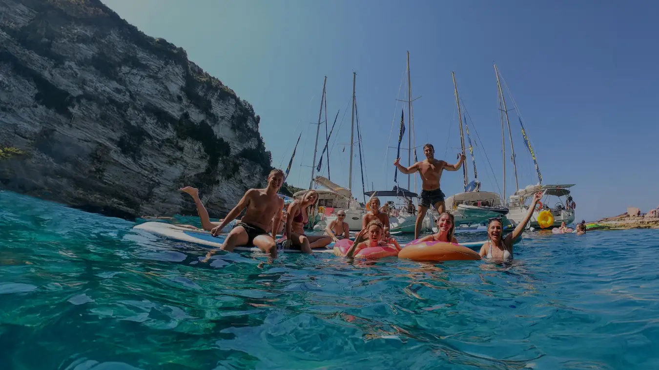 Four women on a paddleboard in clear blue water in Greece
