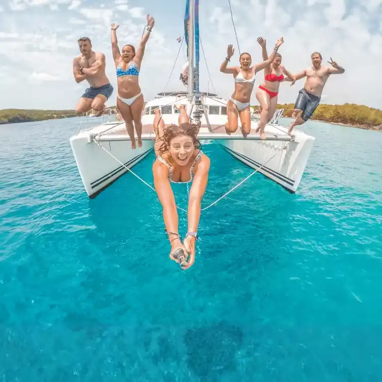 Group of MedSailors travellers jumping into the Mediterranean from their catamaran during a social sailing holiday for 20s and 30s.