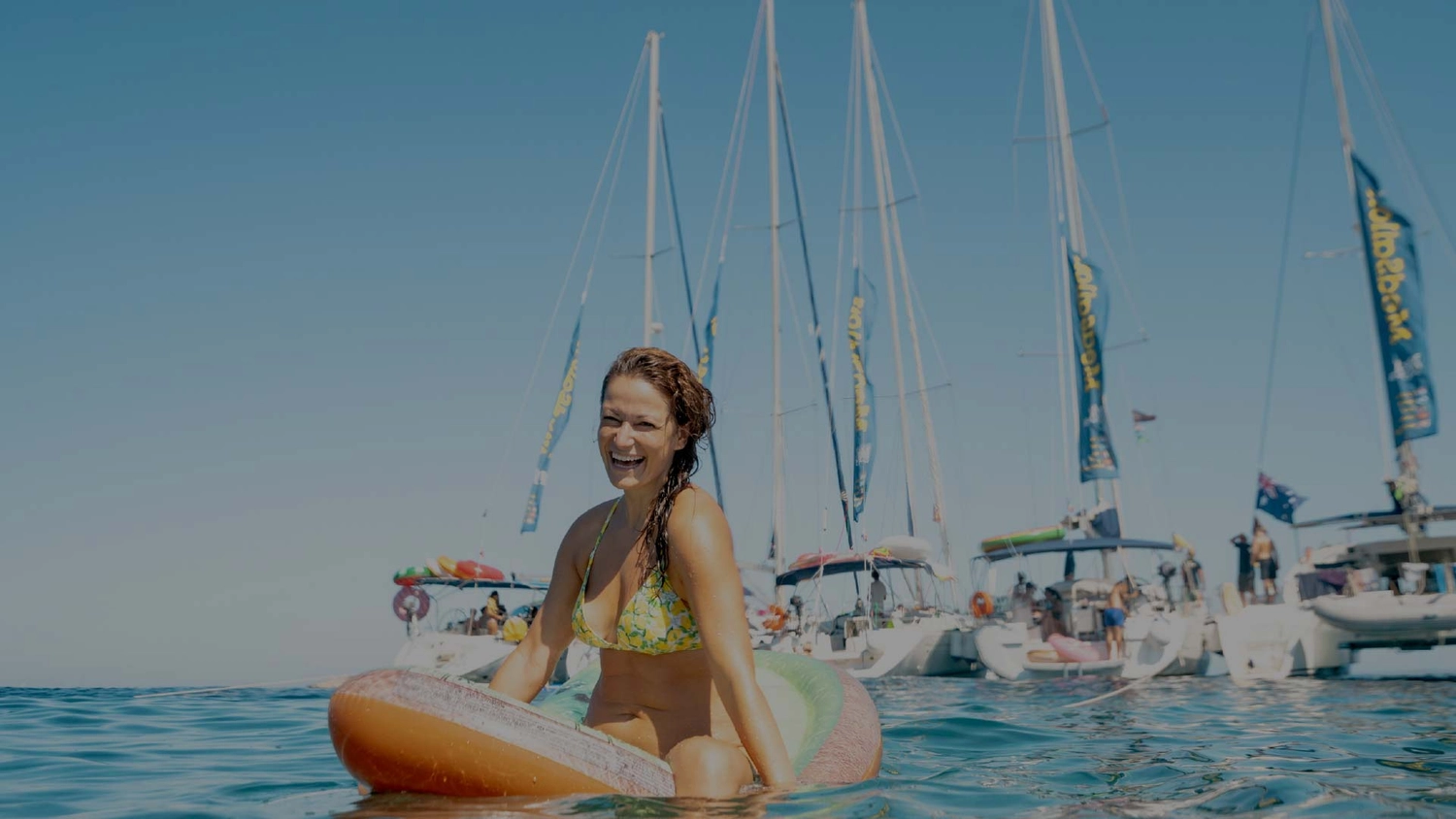 Woman on a floatie in front of a group of yachts