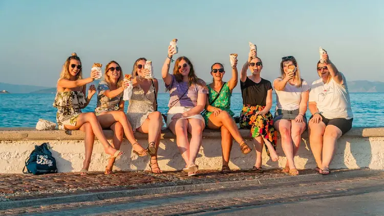 MedSailors travellers enjoying traditional Greek gyros by the sea in Aegina, Greece.