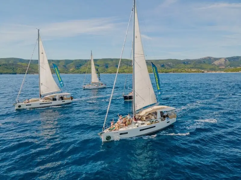 MedSailors sailing yachts cruising along the Croatian coast with travellers on deck and green islands in the background, a popular way to experience Croatia island hopping.