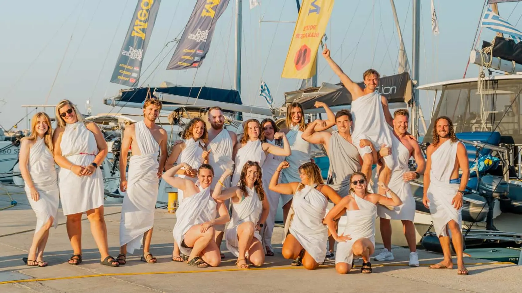 Group of MedSailors guests pose for a photo wearing Greek togas