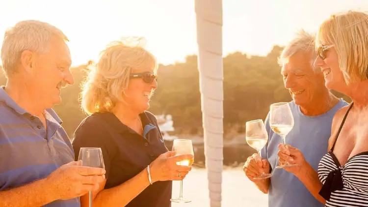 Group of friends drinking wine at sunset on a yacht