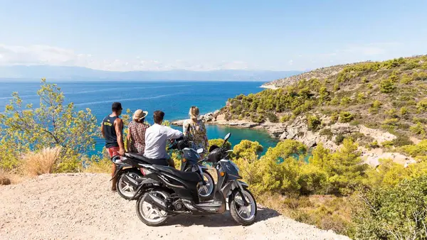 Group of friends sitting next to scooters looking at the view