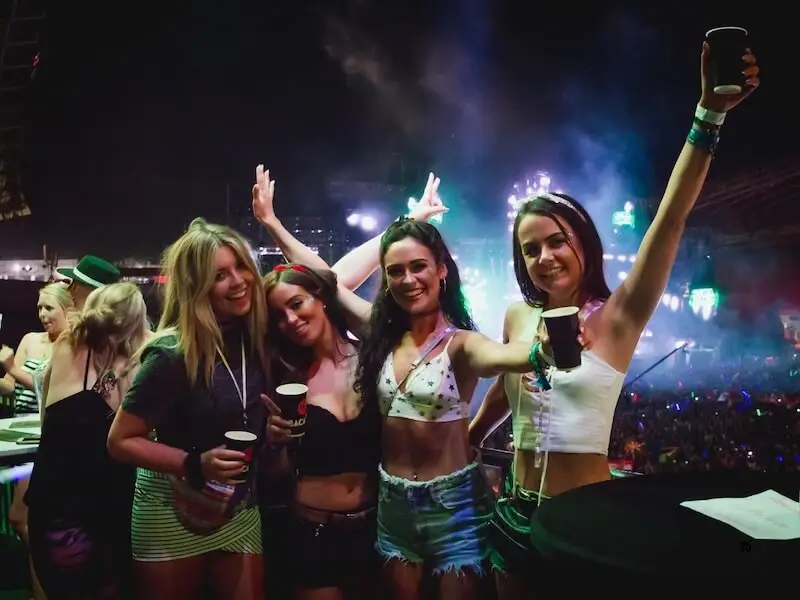 Group of friends enjoying ULTRA Europe at night with festival wristbands and drinks in the crowd.