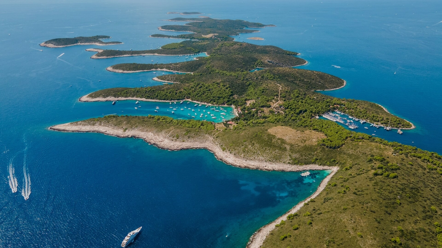 Aerial view of the Pakleni Islands near Hvar in Croatia showing clear blue water, boats in sheltered bays and the coastline used for island hopping guides.