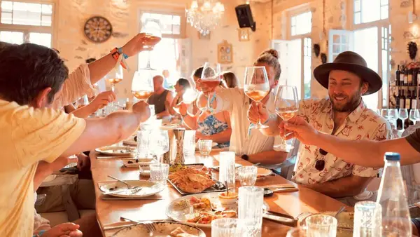 Group of GenZ and Millennial travellers on a social group tour tasting local Greek wine varieties on the island of Poros in the Saronic Gulf, while learning about the history of Greek wine.
