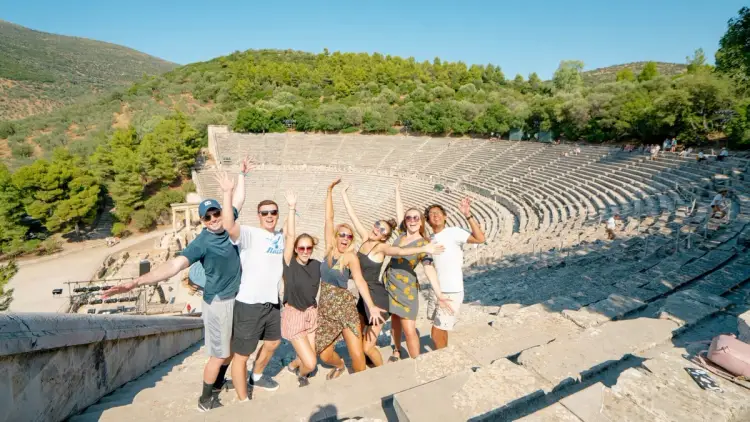 A group of Gen Z and Millennial travellers on a Greece Island Hopping tour standing in Epidavros ancient theater near Athens.