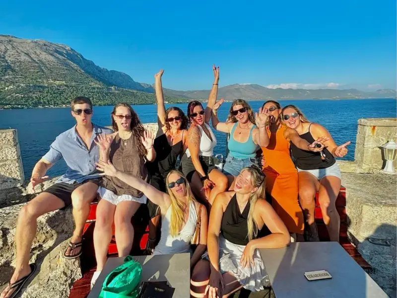 Friends posing at a scenic waterfront stop in Croatia with sea views and mountains behind them during a summer island-hopping trip. This image fits content about ULTRA Europe, things to do beyond the festival, Croatia travel ideas, and pairing Split festival nights with island exploration.