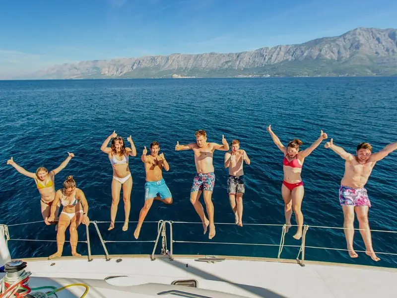 MedSailors travellers jumping from a sailing yacht into the Adriatic Sea during a Croatia island-hopping holiday along the Dalmatian coast.