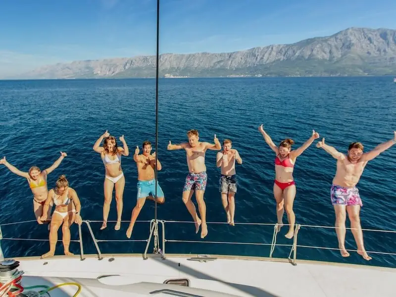 Group of travellers jumping into the sea from a sailing yacht during an island hopping trip along the Croatian coast.