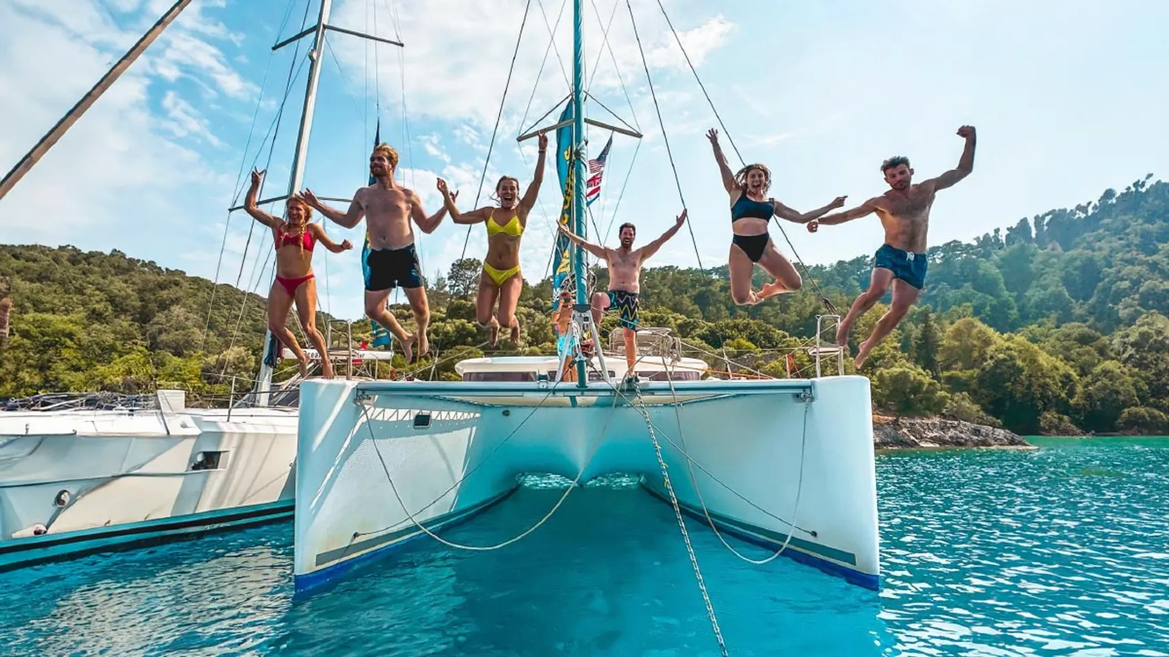 Group of friends jump into the Mediterranean from their catamaran