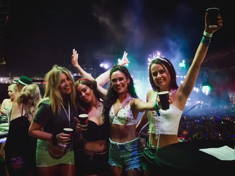 Group of friends enjoying a summer music festival in Croatia with stage lights, crowd atmosphere, and drinks in hand while on a sail week Ultra Croatia with MedSailors.