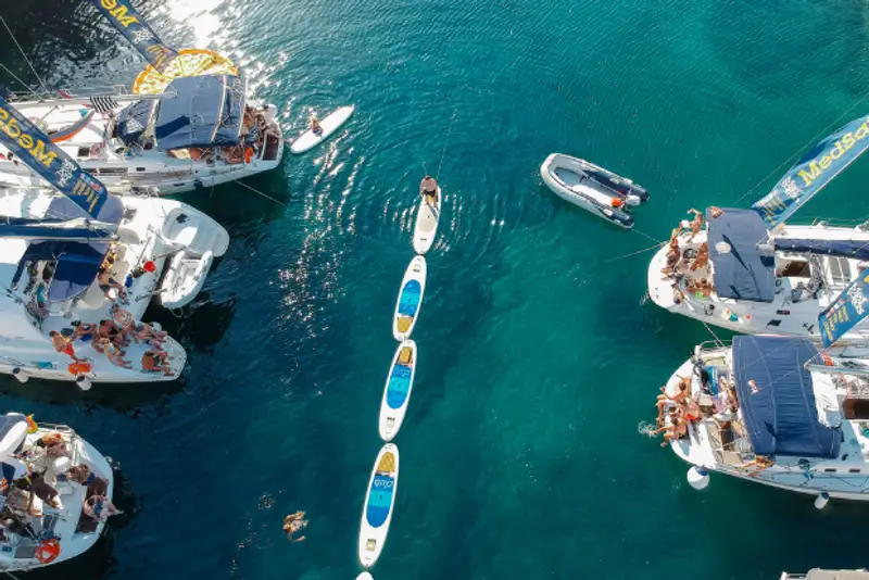 A raft of sailing yachts with paddle boards in the middle