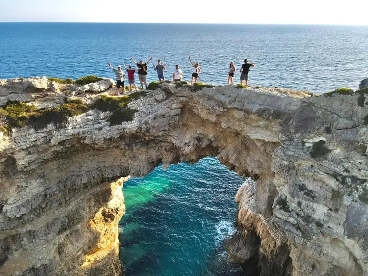 Group pose for a photo on Tripitos Arch in Greece