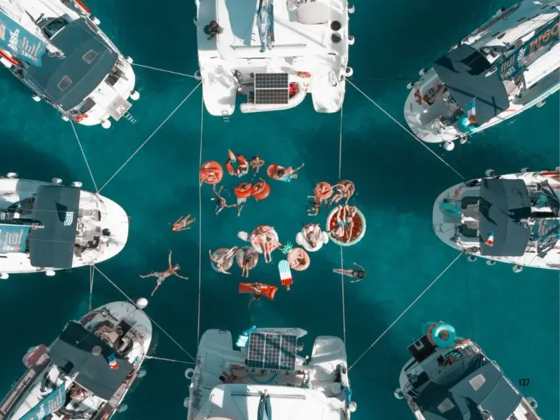 Aerial view of catamarans anchored in clear Adriatic water during a Croatia island-hopping trip, with travellers swimming and relaxing on inflatables between the boats. A strong image for content about ULTRA Europe, Croatia sailing holidays, swim stops, and turning a Split festival trip into a bigger summer adventure.